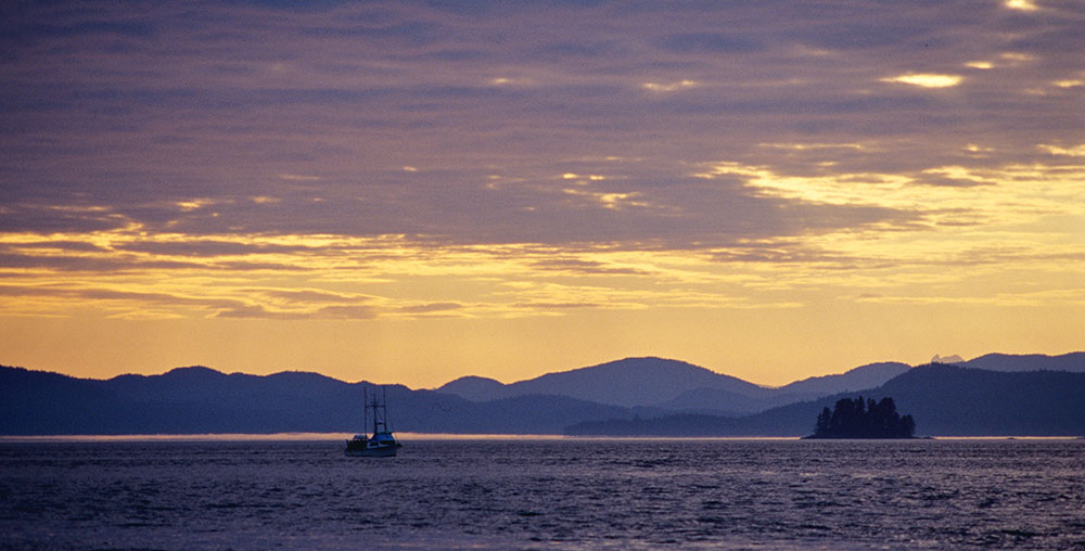 small boat at sunset with rolling hills in the distance